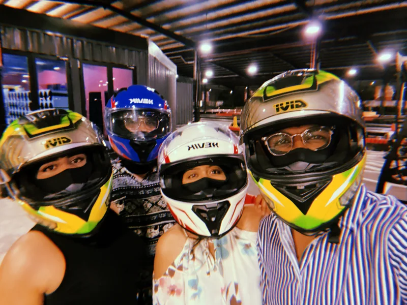 Four friends wearing karting helmets, ready for a race
