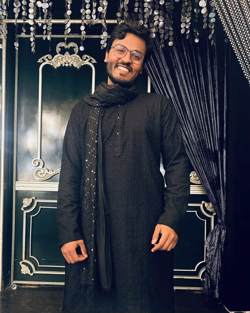 Shivam in dark traditional attire beneath decorative lights