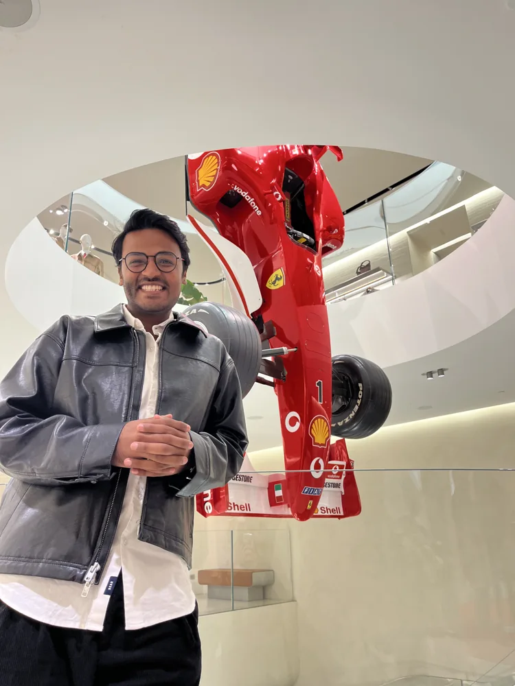 Shivam beside a red Ferrari Formula 1 car on display