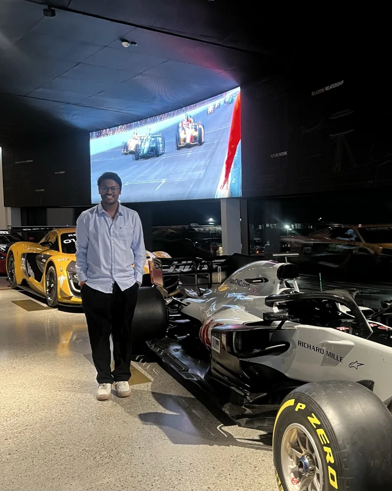 Shivam standing among racing cars in an exhibition